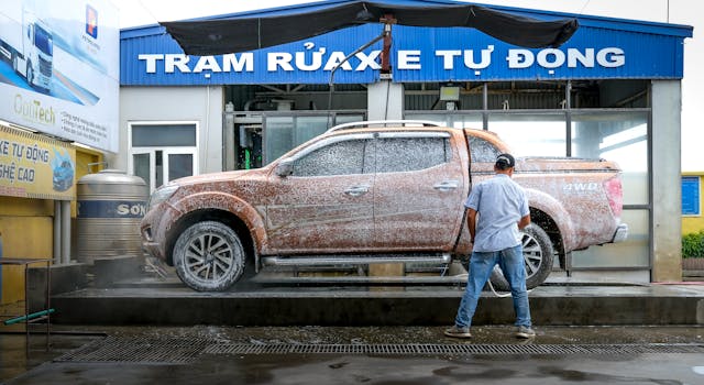 pexels-photo-14023347-14023347 A pickup truck being cleaned at a modern automated car wash facility with a worker present.